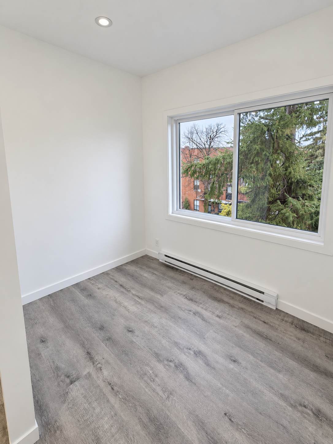 Pièce rénovée avec plancher gris, murs blancs et grande fenêtre