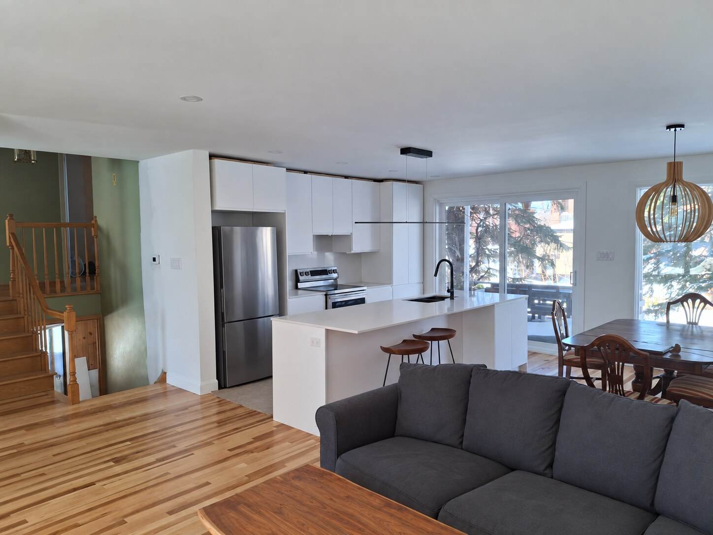 Renovated open white kitchen with a large island, wood flooring and adjoining living space